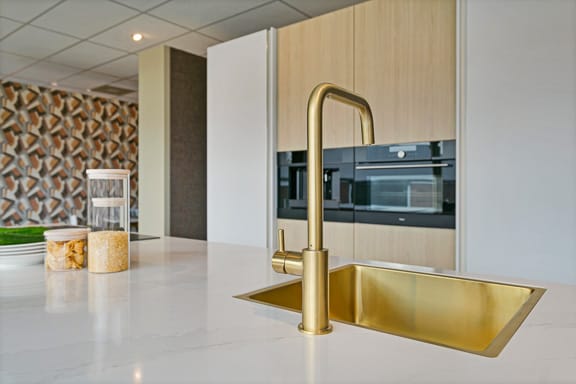 achteromme-nieuwerkerk-smaakvolle-keukens d' Achteromme Nieuwerkerk moderne keuken met goudkleurige kraan en wasbak