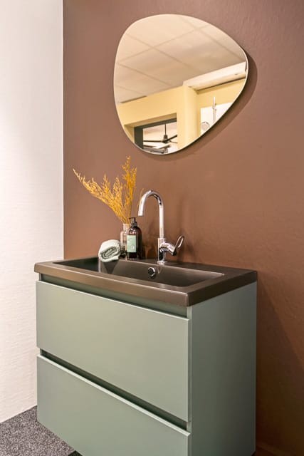 Natuurstenen wastafel met olijfgroene ombouw en bijzondere ovale spiegel